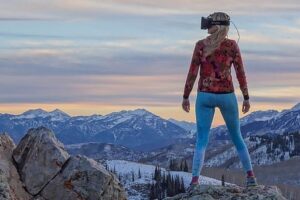 woman stands on top of a mountain wearing VR headset